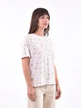 Remera de manga corta color beige con estampado de bananas en tonos amarillo, naranja y rosado.