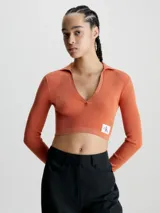 Sweater cropped de Calvin Klein, confeccionado en punto de lyocell con textura acanalada. Presenta cuello tipo polo con escote en pico, mangas largas y una insignia con el monograma de la marca en el bajo.
