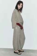 Pantalón de tiro medio con estampado de cuadros vichy en tonos beige y marrón. Cuenta con cintura elástica tipo nido de abeja y bajo ajustable con cordones.