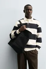 Sudadera de manga larga estilo polo con diseño de rayas horizontales anchas en azul marino y blanco. Presenta cuello de solapa en contraste, cierre frontal con botones ocultos y acabados en rib en puños y bajo.