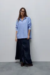 Camisa de manga larga con diseño de rayas verticales blancas y verdes, calce relajado, cuello clásico y botonadura frontal con botones perlados.