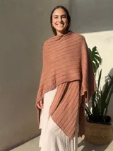 Ruana tejida en punto jersey, color negro con destellos brillantes de lurex. Presenta una etiqueta de cuero sintético con logo en la parte posterior.