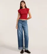 Top ajustado color rojo, con cuello redondo y mangas cortas tipo hombreras o almohadillas. El tejido parece ser de punto o viscosa con buena caída y presenta un fruncido horizontal a la altura de la cintura.