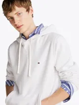 Buzo blanco de Tommy Hilfiger con capucha, cordones ajustables, logo bordado en el pecho, bolsillo tipo canguro, puños y bajo acanalados. Confeccionado en mezcla de algodón y poliéster.