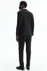 Pantalón de traje de corte ajustado, con cierre y corchete oculto, bolsillos laterales y bolsillos traseros ribeteados. Presenta raya marcada en las piernas y diseño con margen de costura en la pretina.