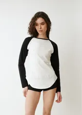 Remera de manga larga estilo raglan, color verde militar, con cuello redondo y dobladillo inferior curvado.