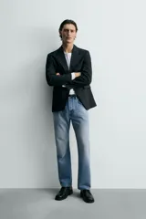 Jeans de mezclilla rígida de algodón, color azul claro con efecto lavado y ligero desgaste. De tiro medio, corte recto desde la cadera hasta la rodilla y ligeramente acampanado en el bajo (bootcut). Cierre frontal con botonadura y cinco bolsillos.