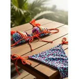Conjunto de bikini compuesto por un corpiño triángulo naranja liso con tirantes decorados con volados fruncidos y una bombacha tipo tanga con estampado animal print en tonos celeste, fucsia y negro, con tiras laterales ajustables.