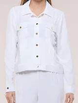 Camperita liviana de corte recto y acabado crepé color blanco, con cuello camisero clásico y cierre frontal de botones metálicos dorados. Presenta bolsillos en el pecho con solapa y mangas largas con puños abotonados.