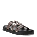 Sandalias planas Miss Carol modelo Nevada, color marrón, con tres tiras en el empeine decoradas con tachas metálicas plateadas. Una de las tiras cuenta con una hebilla de ajuste lateral. Poseen suela y plataforma baja de color negro.
