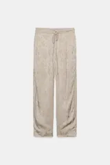 Pantalón de tiro medio de ZARA WOMAN COLLECTION, confeccionado en hilatura de viscosa con tejido jacquard de estampado floral sutil en tono beige. Presenta pierna ancha, acabado en pliegue y cintura ajustable con cordón de lazada.