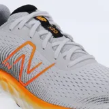 Championes de running New Balance modelo 520, color blanco con detalles en naranja y negro. Presentan capellada de tejido mesh transpirable, entresuela de espuma EVA para amortiguación y suela de caucho con tracción.