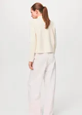 Sweater de punto fino color blanco marfil, de corte recto, con cuello perkins y manga larga.