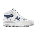 Championes New Balance modelo 650, de caña media, con diseño en cuero blanco y detalles en azul marino y gris. Presenta perforaciones laterales, logo N característico y suela de goma.