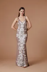 Vestido largo de fiesta con capa integrada, confeccionado en tela fluida con estampado botánico barroco en tonos marrones y crema. El diseño presenta un corte ajustado al cuerpo con escote asimétrico y una capa superpuesta que aporta movimiento y elegancia.