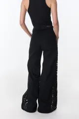 Pantalón de jean azul oscuro de pierna ancha y tiro medio, con paneles laterales en contraste de color marrón. Presenta costuras pespunteadas en tono tostado y terminación desmechada en el bajo.