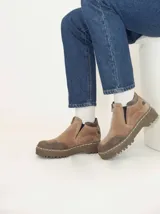 Bota corta de gamuza en tonos arena y marrón, con diseño tipo tracker. Presenta cierre frontal, elásticos laterales ocultos para mayor comodidad y suela de goma dentada cosida.