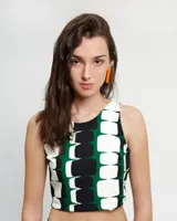 Top corto de cuello a la base y corte halter, confeccionado en crepe. Presenta un estampado geométrico en tonos verde, negro y blanco, con cierre lateral y abertura con botón en la espalda.