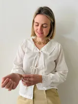 Camisa blanca de mangas largas con cuello babero y puños de puntilla, con lazos en el escote.