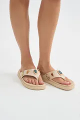 Ojotas de dedo negras con suela plana y gruesa, decoradas con apliques metálicos de piedras de colores en la tira.