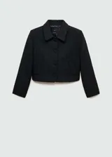 Chaqueta corta de tejido tweed en color negro, con cuello camisero, manga larga y cierre frontal con botones forrados. Presenta un diseño recto con dos bolsillos laterales.