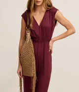 Mono largo de viscosa color borgoña, con corte flare, escote en V, sin mangas, elástico en la cintura y lazo en el cuello.