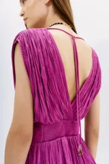 Vestido corto de color fucsia, confeccionado en tela con efecto crinkle. Presenta un diseño sin mangas con escote en V profundo tanto en el frente como en la espalda, cintura marcada y falda con volados. Incluye tiras de ajuste en los hombros con terminaciones metálicas.