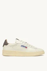 Zapatillas urbanas Autry modelo Dallas Low, color blanco hueso con detalles en marrón en el talón y logo de la marca en el lateral.