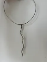 Gargantilla plateada con dije colgante en forma de serpiente ondulada.