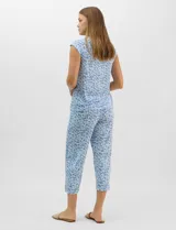 Pijama compuesto por remera sin mangas con escote redondo, botones frontales y detalle de puntilla, acompañado de un pantalón capri con cintura elástica. Presenta un estampado floral en tonos rosados sobre base gris.