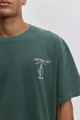 Remera de algodón color verde oscuro, de corte holgado y manga corta, con pequeño estampado gráfico en el pecho.