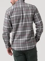 Camisa de manga larga confeccionada en franela de algodón orgánico cepillado, con diseño de cuadros en tonos grises, blancos y líneas finas en color bordó. Presenta cuello clásico, cierre frontal con botones de madera y dos bolsillos frontales en el pecho.