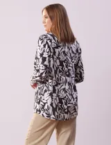 Camisa de lino estampada en blanco y negro con diseño de hojas, marca Zac & Rachel. Tiene cuello con solapa, abertura central con botones, bolsillo aplicado en la parte delantera y mangas largas regulables con presilla y botón.