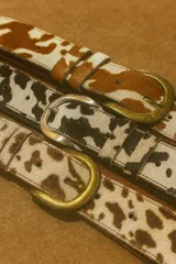 Cinto de cuero vacuno con pelo natural, con hebilla metálica y costuras reforzadas.