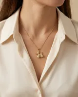 Cadena de acero con baño de oro y dije en forma de perrito hecho con globos, decorado con circonias brillantes.