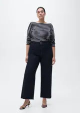 Pantalón de jean tiro alto con corte culotte y pernera ancha. Presenta cierre frontal con cremallera y botón, trabillas para cinturón, bolsillos traseros y bajo con acabado deshilachado.