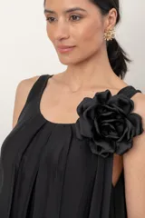 Vestido midi de gasa negro, con solera sin mangas, escote fruncido y detalle de aplique floral en el hombro.