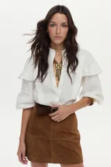 Camisa blanca de lino con cuello mao, volados en los hombros y mangas abullonadas con elástico. Cierre frontal con botones.