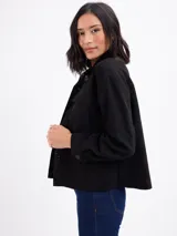 Chaqueta de gamuza sintética color negro, con cuello camisero, bolsillos frontales con solapa, cierre de botones y mangas largas.