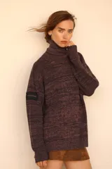 Polerón de tejido de punto con efecto nevado, cuello alto y mangas largas. Presenta un diseño holgado y un parche decorativo en la manga derecha.