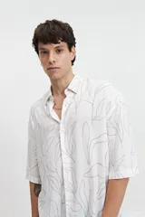 Camisa oversize de manga corta con cuello clásico y estampado abstracto en tonos grises.