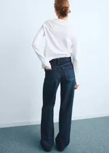 Jeans tiro alto wide leg de color azul, con diseño de cinco bolsillos, presillas para cinturón y cierre frontal con cremallera y botón.