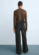 Pantalón de jean tiro alto con diseño wide leg, confeccionado en tejido de algodón con elasticidad. Cuenta con cierre frontal de cremallera y botón, trabillas para cinturón y cinco bolsillos.