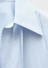 Camisa de corte oversize y diseño largo, confeccionada en algodón. Presenta cuello camisero, escote en V profundo con tiras largas integradas y mangas largas con puños abotonados.