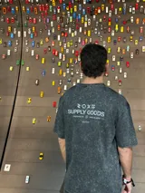 Remera gris con efecto gastado, corte oversize, mangas cortas y estampado en la espalda con el texto "SUPPLY GOODS DESIGNED IN PUNTA DEL ESTE".