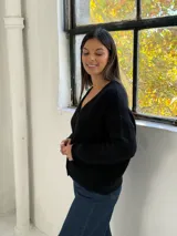 Saco tipo cardigan de punto color negro, con cuello en V, cierre frontal con botones y mangas largas con puños acanalados.