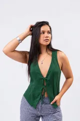 Chaleco verde oscuro de lino con escote en V profundo y cierre frontal con tres lazos para atar en forma de moño.