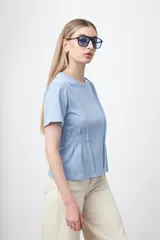 Remera de manga corta y cuello redondo, confeccionada en algodón. Presenta costuras verticales visibles en el frente que generan un efecto de entalle y estructura en la cintura.