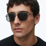 Lentes de sol con montura metálica de acero inoxidable en color gris mate y diseño geométrico inspirado en el estilo aviador. Poseen lentes polarizadas de color negro con protección UV400.