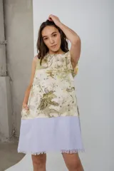 Vestido corto sin mangas, con estampado de hojas en tonos beige y verde, y falda color lila con detalle de flecos en el ruedo.